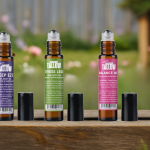 Three Lulu’s Untainted Tallow roll-on body oils—Sleep Eze, Stress Less, and Balance Me—displayed on a wooden surface with a blurred garden background